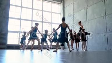 芭蕾舞学校的女舞蹈演员学会跳舞。 穿着黑色舞服训练的小芭蕾舞女。 孩子们`芭蕾